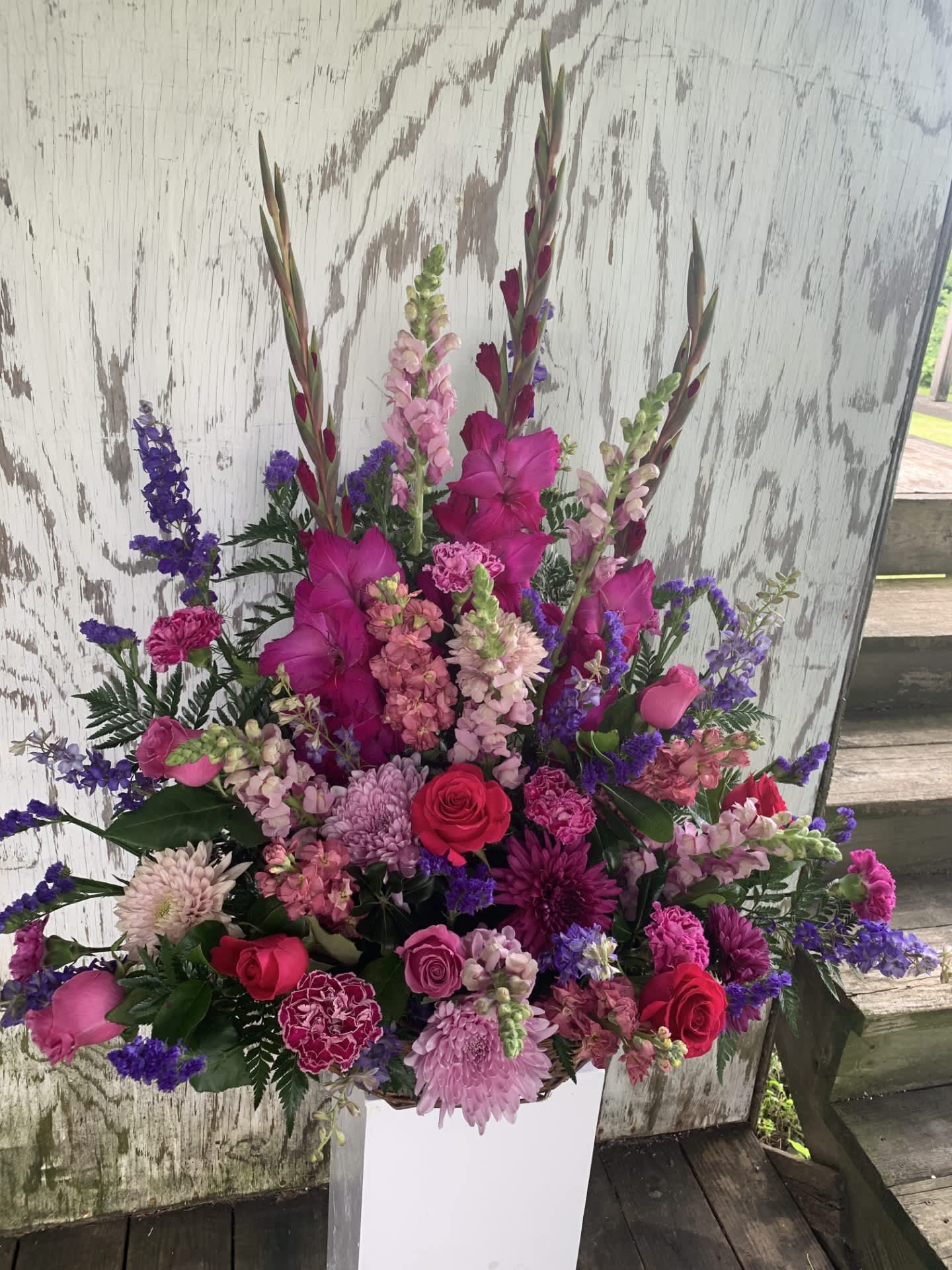 Tall pink and purple floral arrangement in a white vase