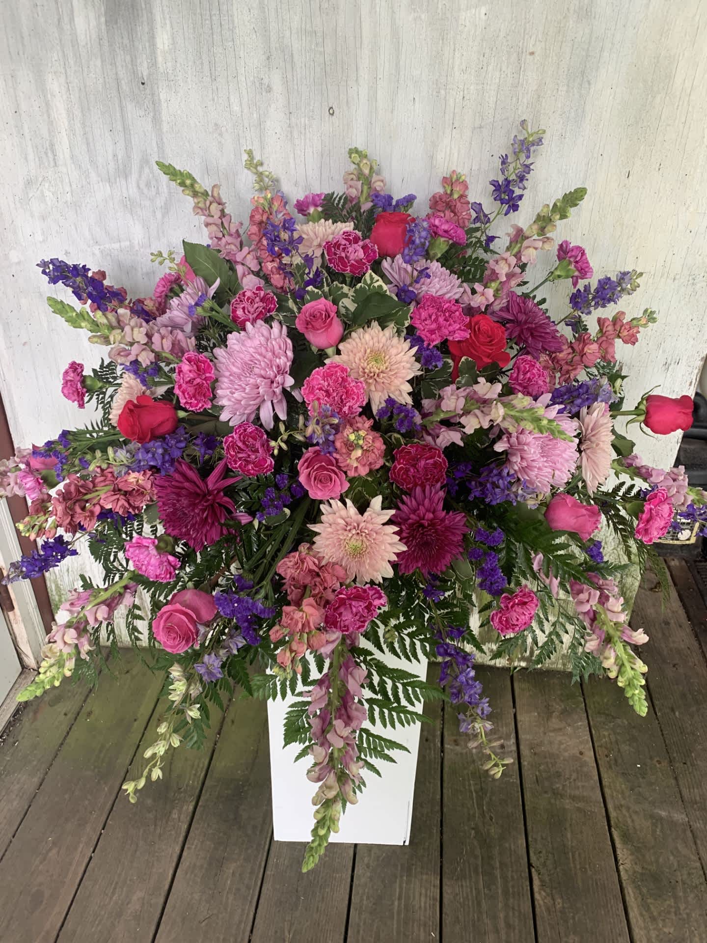 Large pink and purple floral arrangement in a white pedestal vase