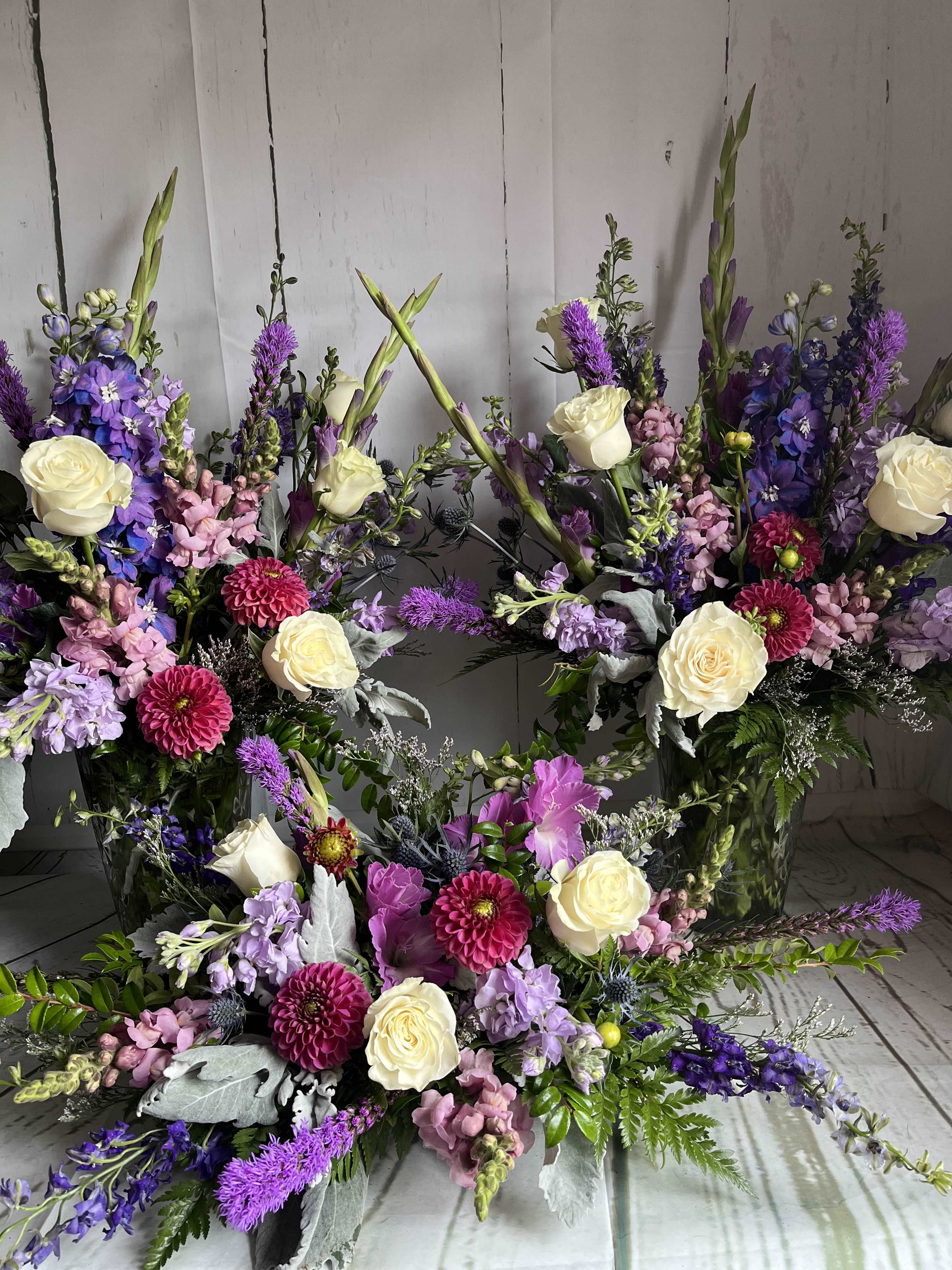 Large floral arrangement with cream roses, purple blooms, and pink flowers