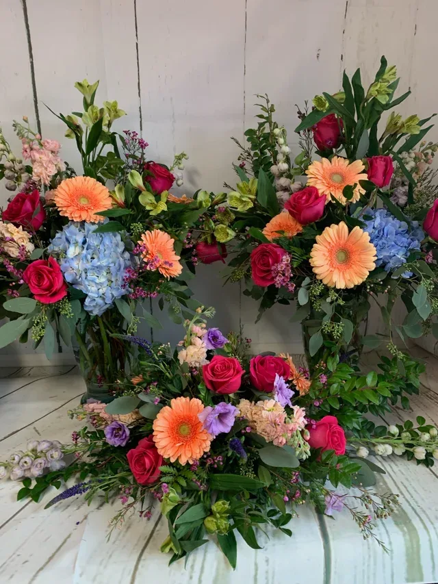 Three colorful floral arrangements with roses, gerbera daisies, and hydrangeas