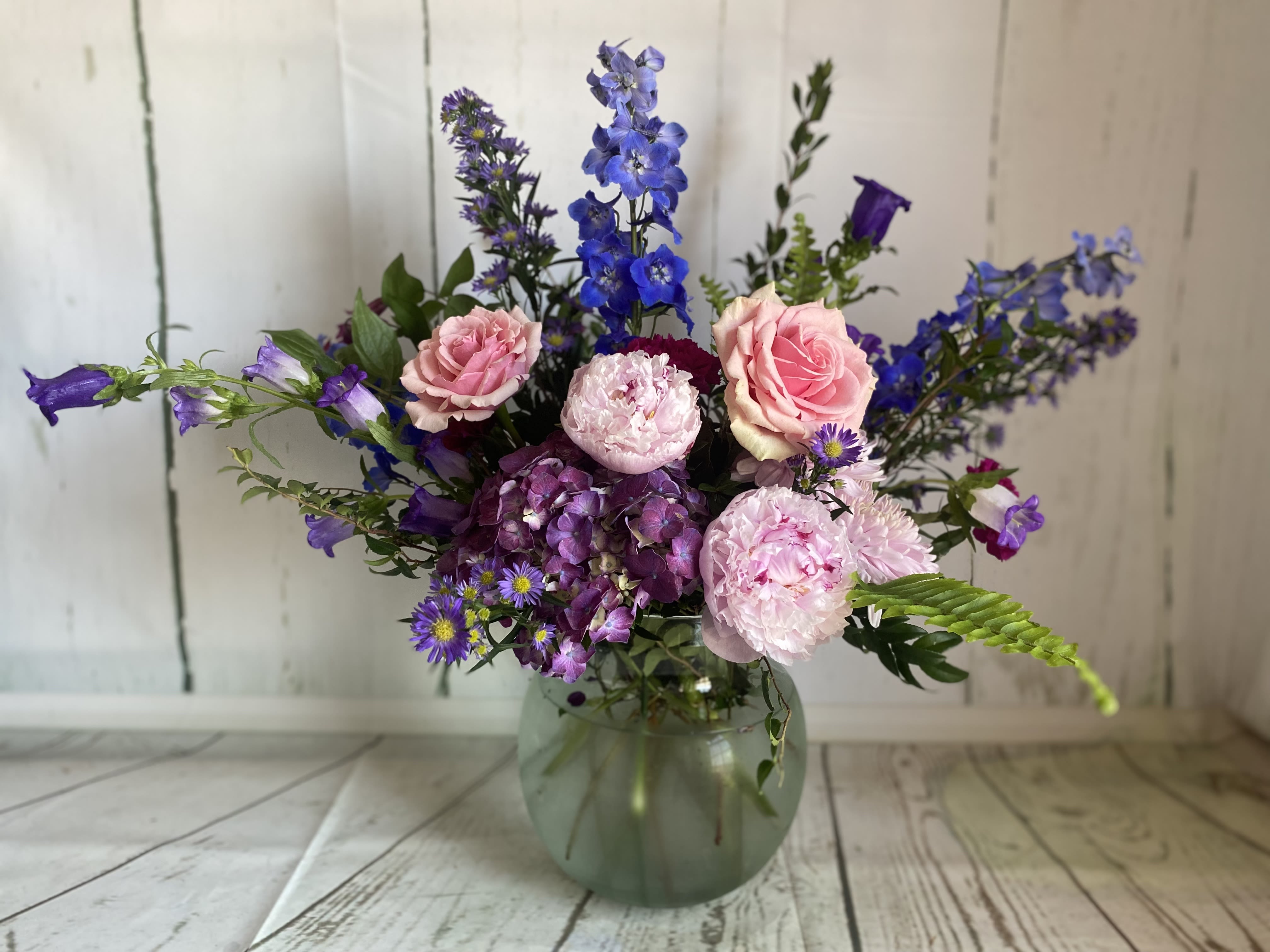 Pink roses and purple flowers arranged in a glass vase