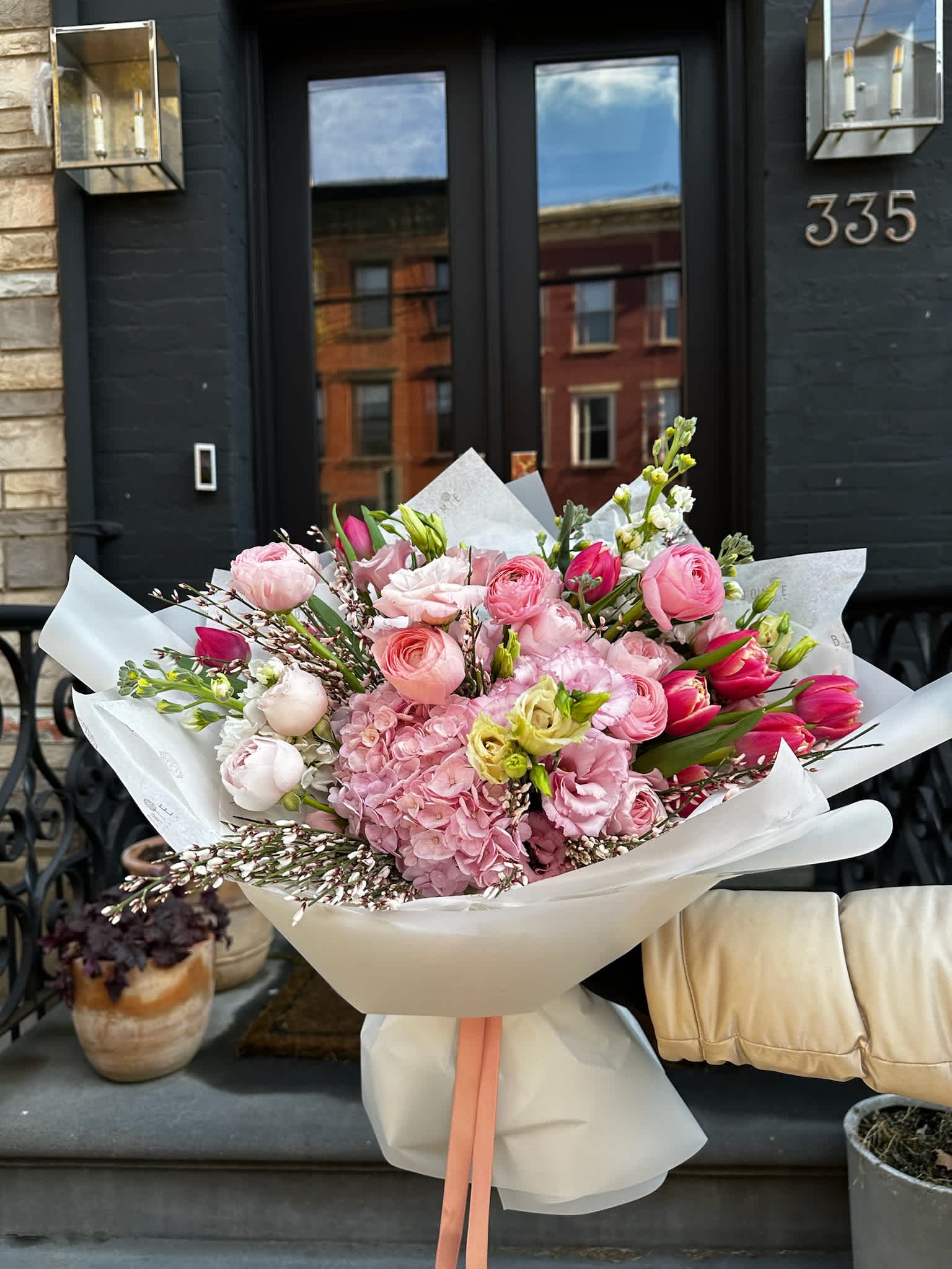 Large pink bouquet wrapped in white paper with a peach ribbon
