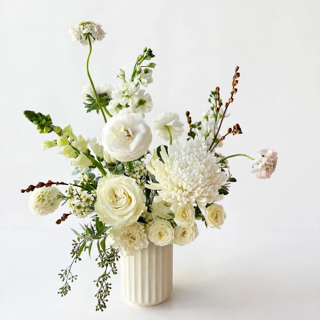 White floral arrangement in a ribbed cream vase
