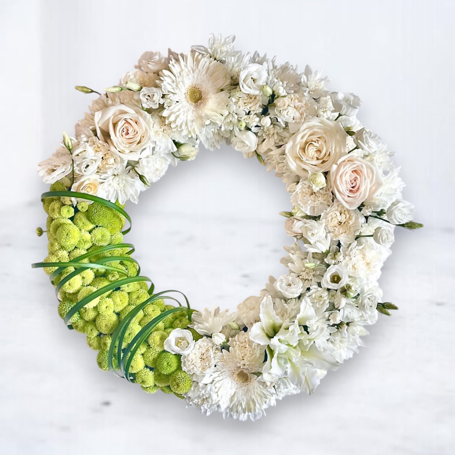 Circular floral wreath with white and cream blooms and a bright green section