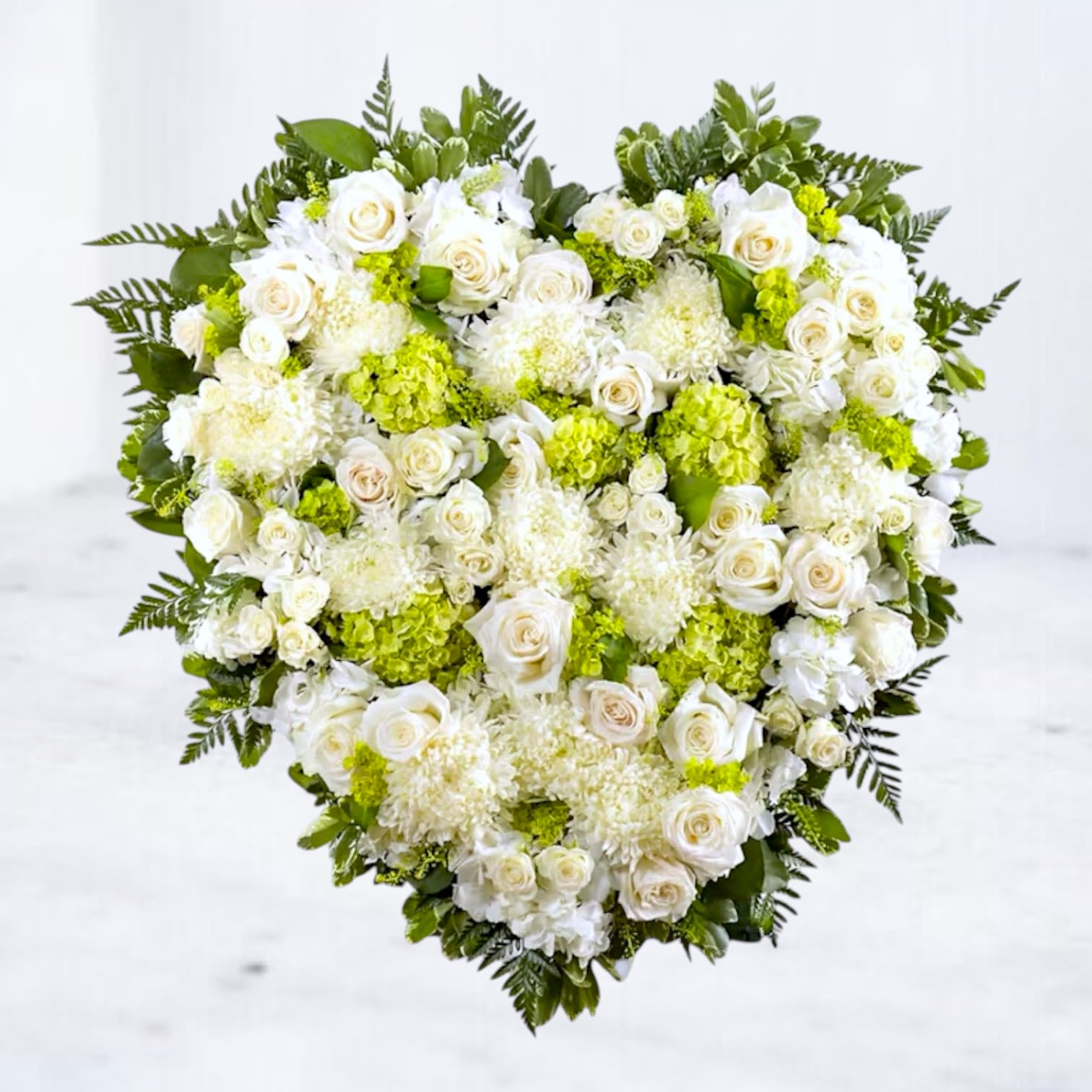 Heart-shaped floral arrangement of white roses and green hydrangeas