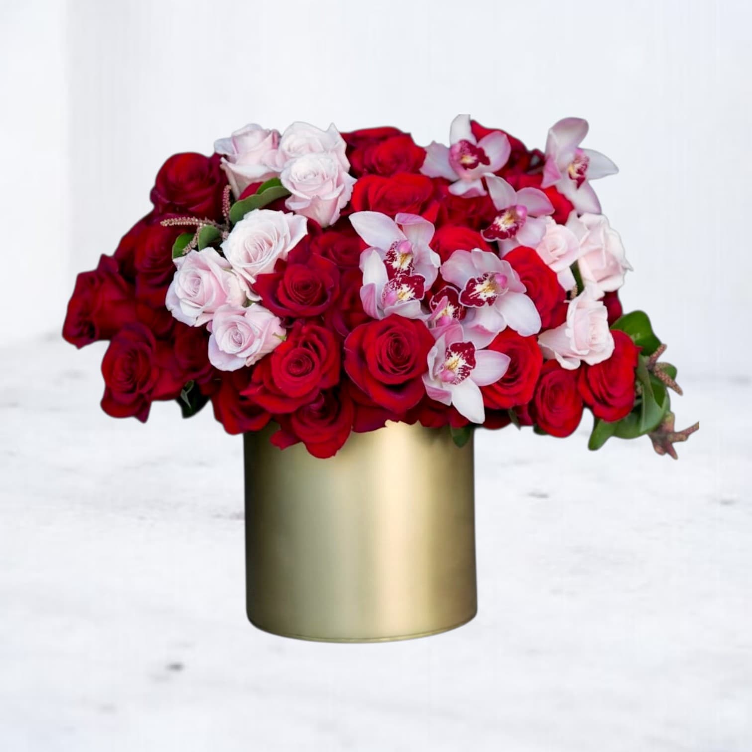 Red and pale pink roses with white orchids in a gold vase