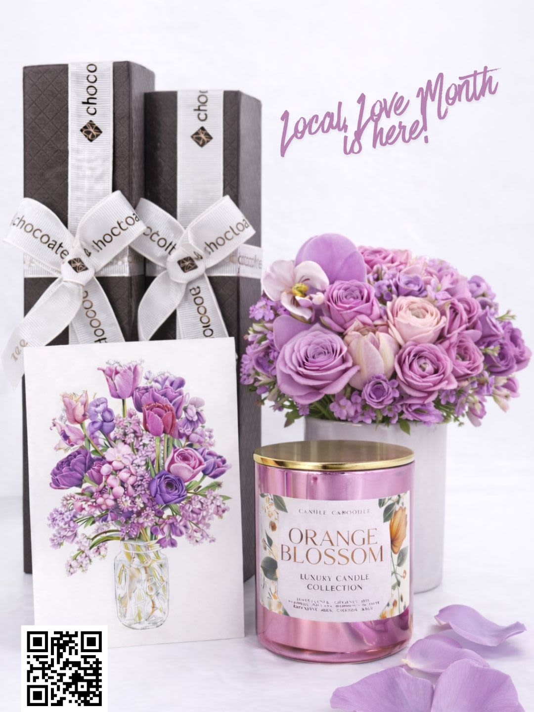 Gift set with purple flowers, chocolate boxes, and a pink candle
