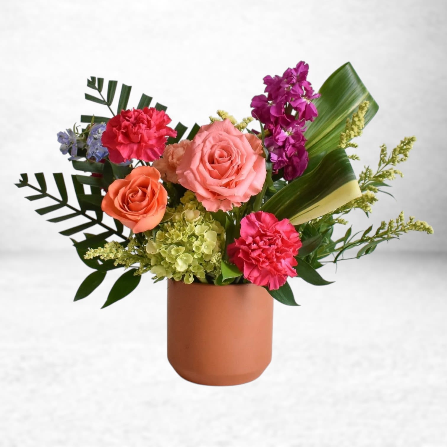 Tropic Bloom Pulse - Tropic Bloom Pulse bursts with vibrant energy, blending tropical greens with bold coral roses, hot pink carnations, vibrant stock, lush hydrangea, and accent blooms. Nestled in a modern terracotta-style vase, this arrangement brings a lively, cheerful vibe perfect for birthdays, get well wishes, congratulations, or to brighten someone’s day. Handcrafted and delivered by Twigs and Blooms in Friendswood, Texas with same-day flower delivery available to League City, Dickinson, Alvin, Galveston, and surrounding areas.  Substitution Policy: At Twigs and Blooms, we prioritize using the freshest seasonal blooms. Occasionally, substitutions may be made to ensure your order arrives fresh and beautiful while maintaining the same design aesthetic, color palette, and overall value.