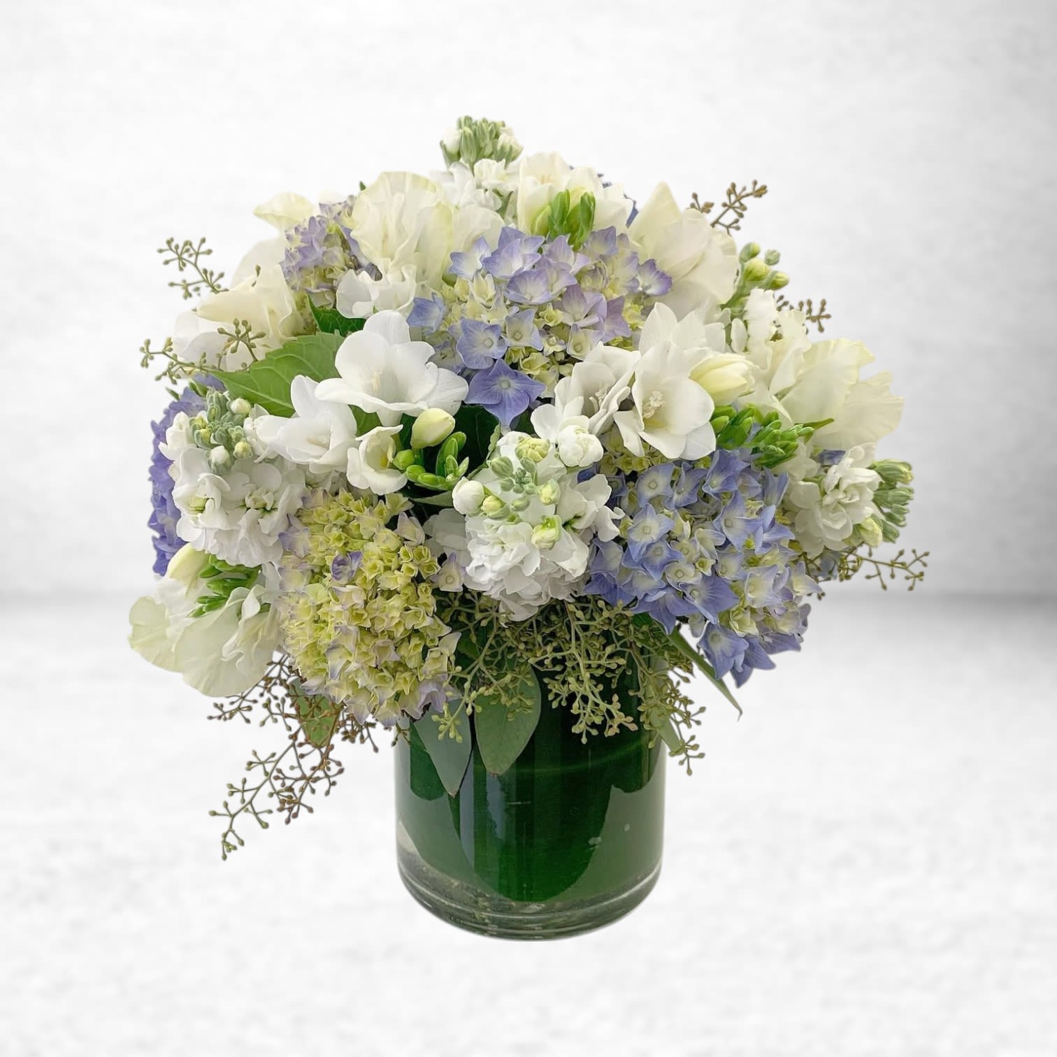 Ocean Breeze Comfort - The Ocean Breeze Comfort arrangement offers a serene blend of soft blues, creamy whites, and gentle greens — a perfect gesture for expressing sympathy, offering comfort, or letting someone know you are thinking of them. Featuring delicate hydrangea, stock, freesias, lisianthus, and seasonal accents, this peaceful design radiates tranquility and heartfelt care. Available for same-day delivery in Galveston, Friendswood, League City, Dickinson, Alvin, and the surrounding Texas Gulf Coast communities, Ocean Breeze Comfort provides an elegant way to share your compassion and support.  Substitution Policy: Each arrangement is crafted with the freshest blooms available. In rare instances, substitutions of equal or greater value may be necessary while maintaining the design’s overall look, feel, and sentiment.  