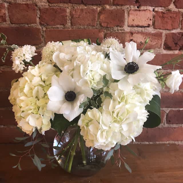 White floral bouquet in a glass vase with anemones and hydrangeas