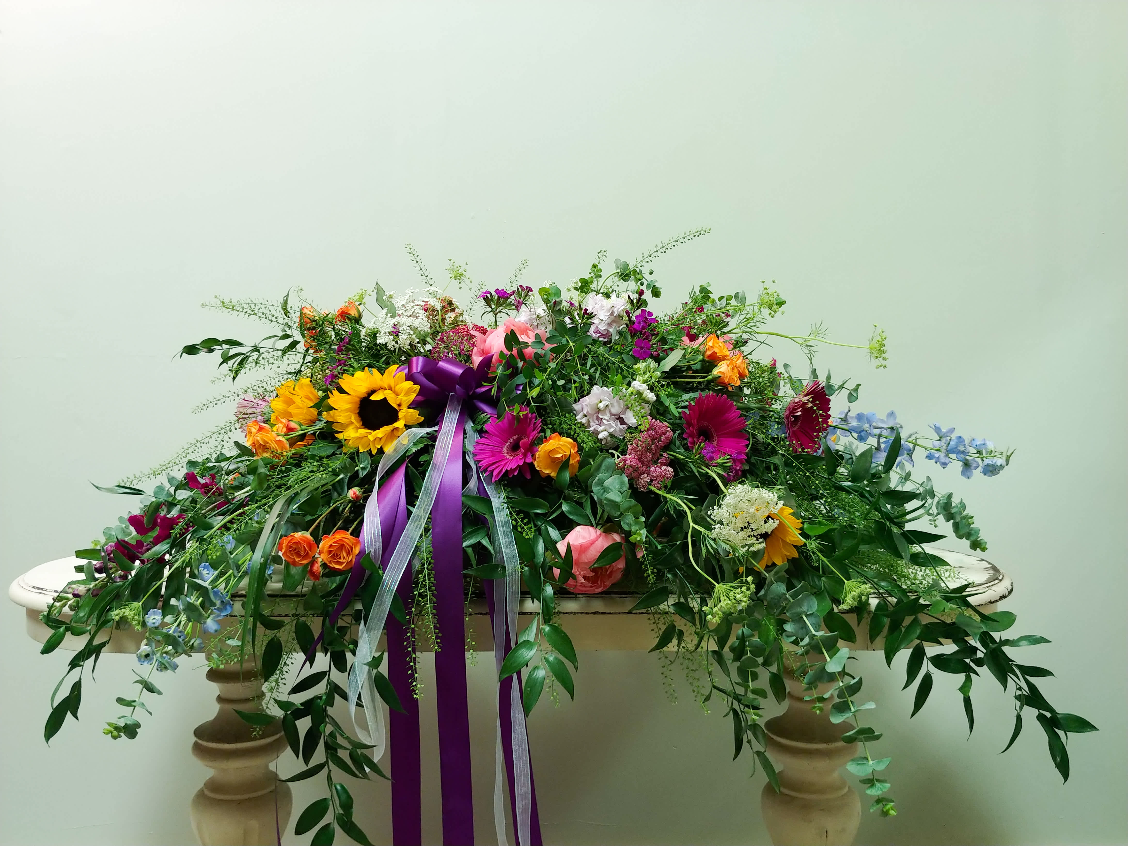 Large colorful floral casket spray with ribbon on a table