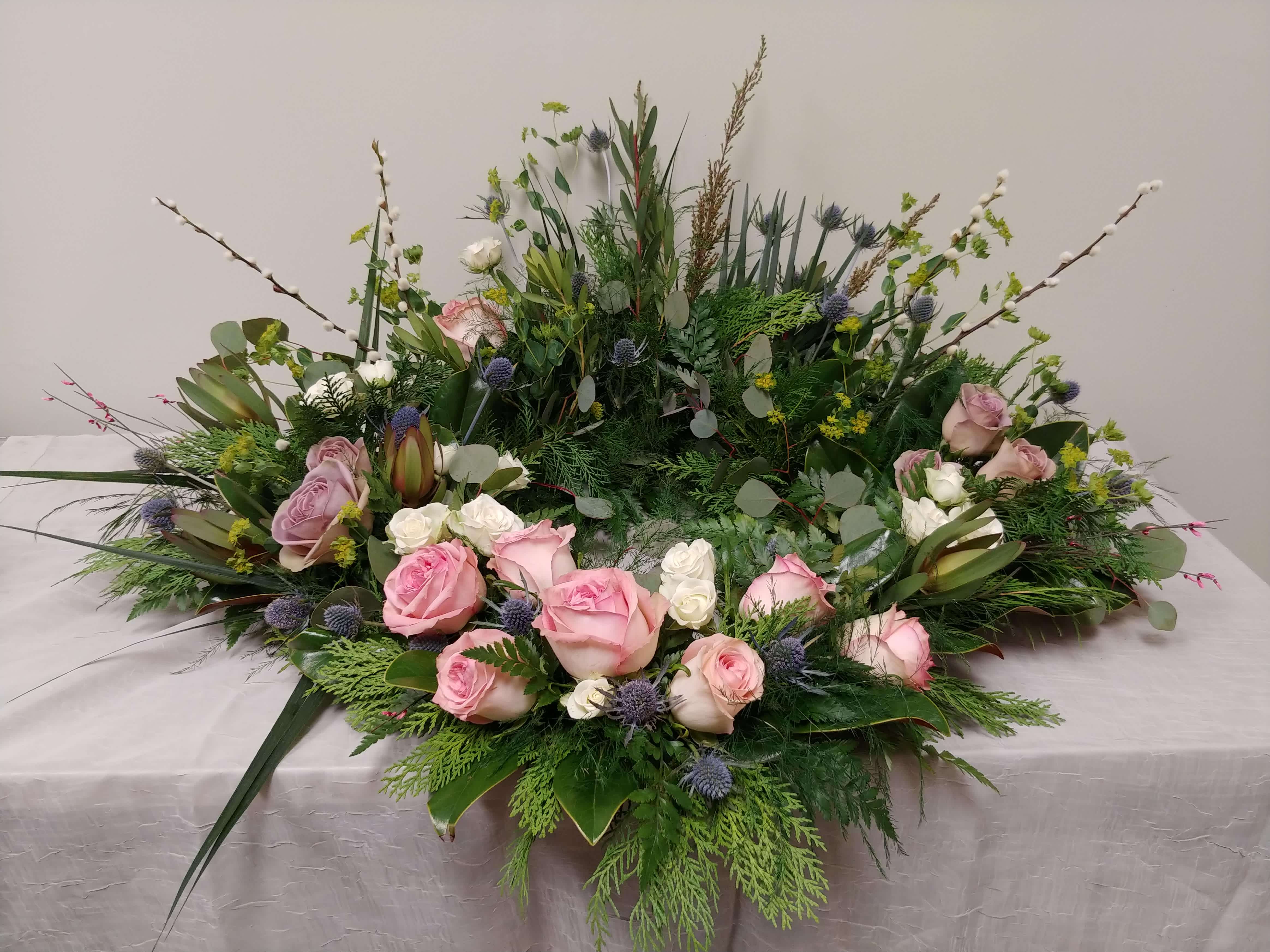 Large floral wreath with pink roses and greenery on a table