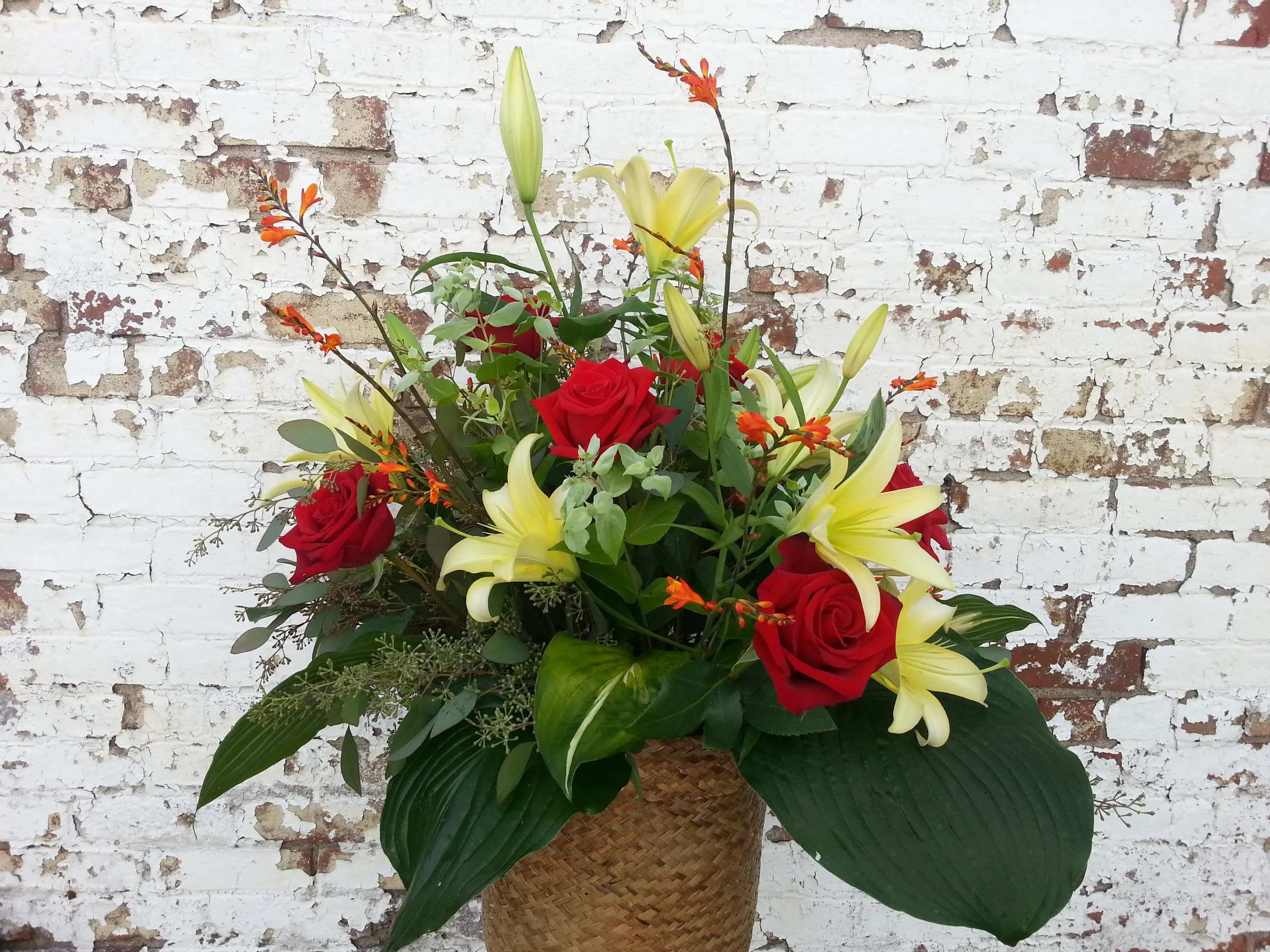 Red roses and yellow lilies in a woven basket