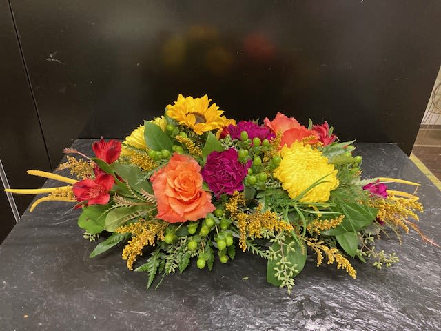 Colorful mixed flower arrangement with roses and sunflowers on a dark surface