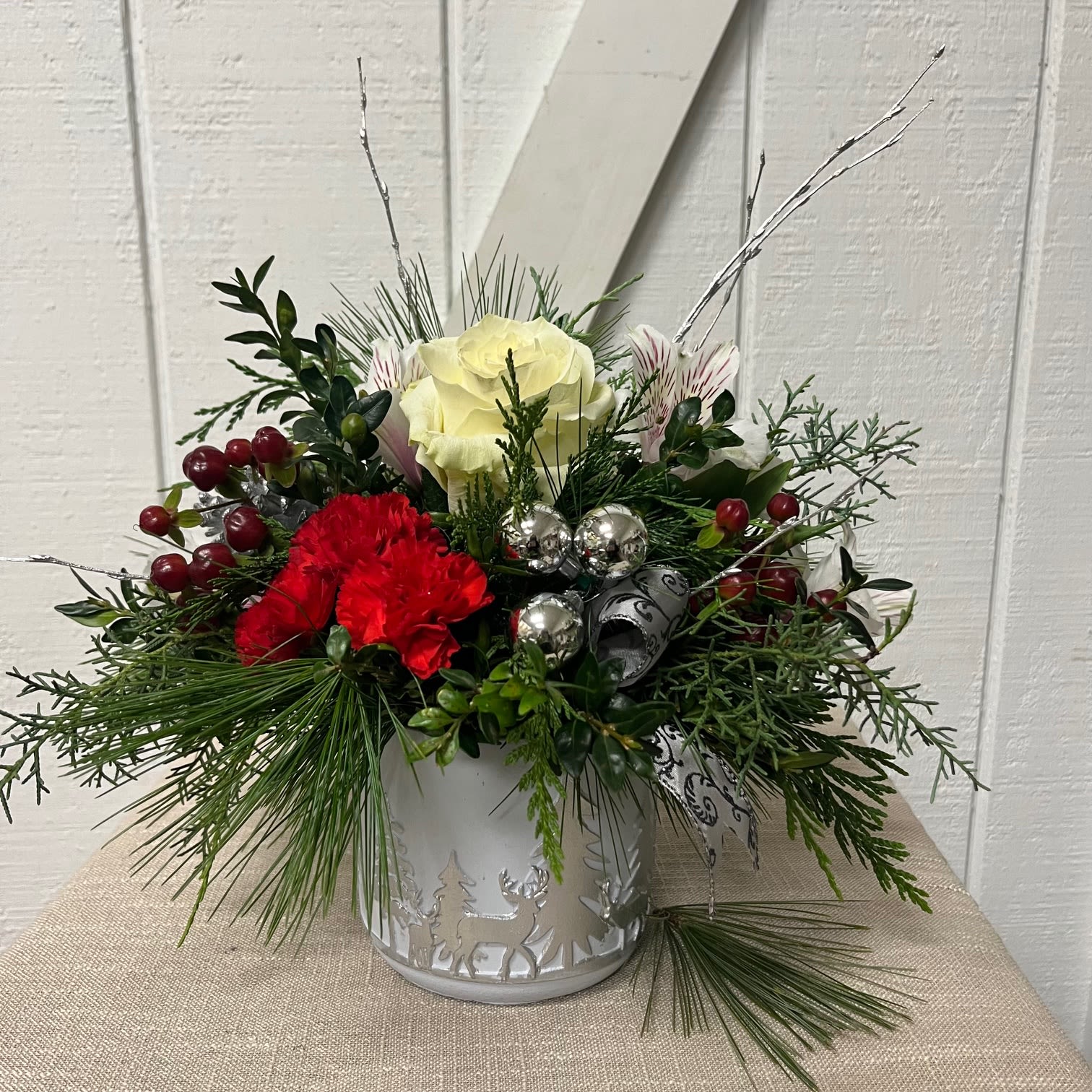 Holiday floral arrangement in a white metal container with red and white blooms
