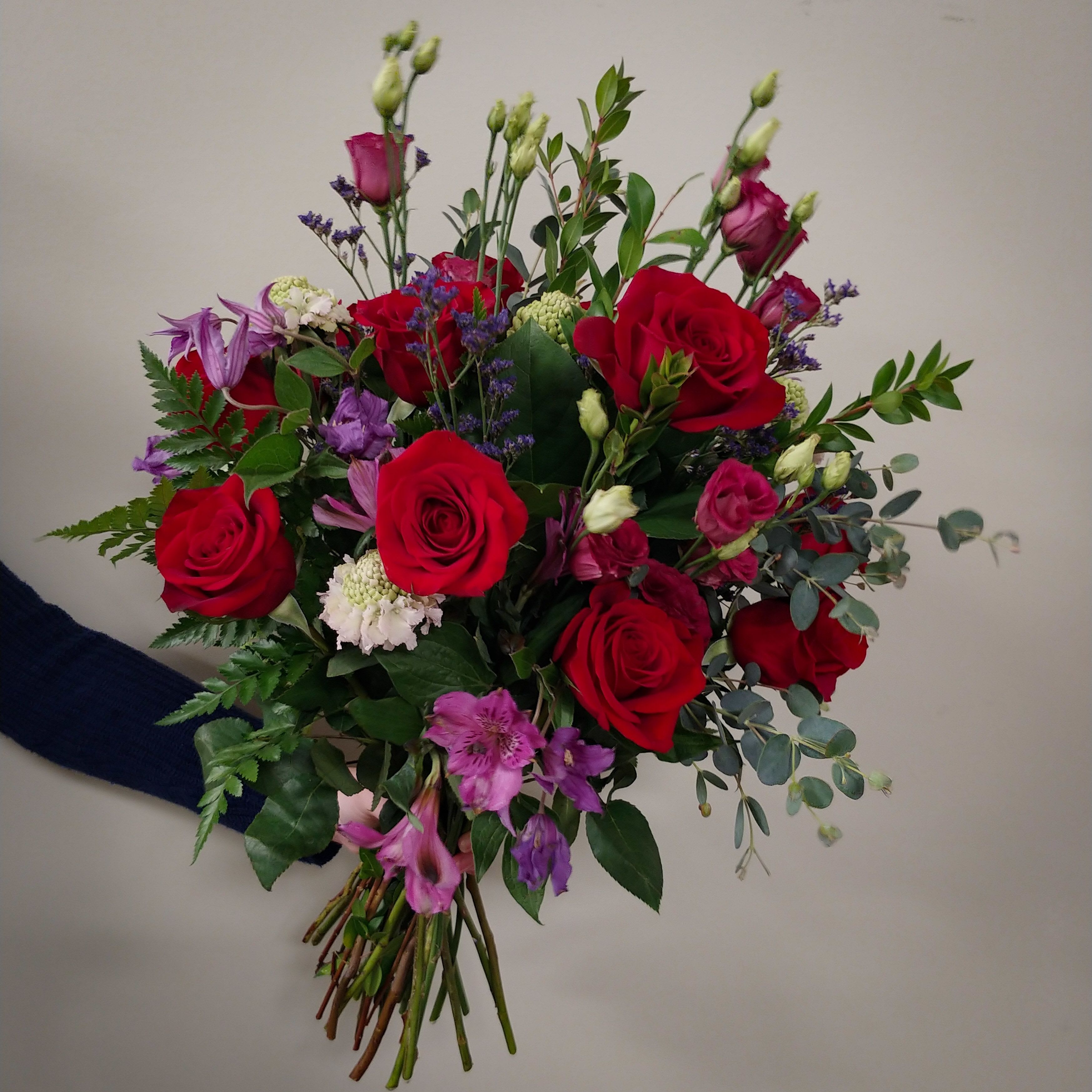 Hand-tied bouquet of red roses and purple flowers
