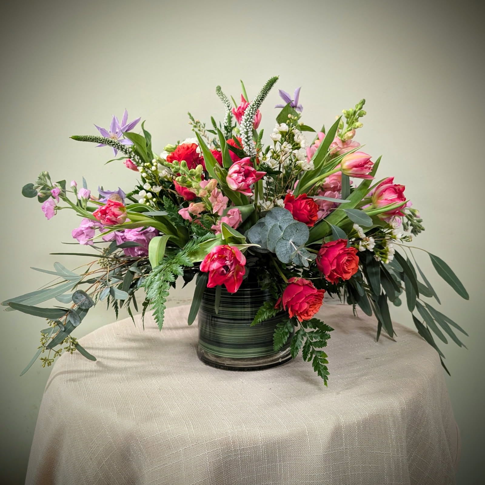 Mixed bouquet of pink and purple flowers in a striped glass vase