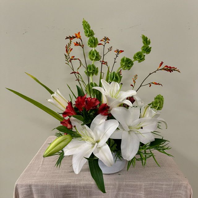 White lilies and red flowers in a white vase