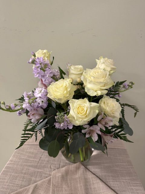 White roses and lavender flowers arranged in a glass vase