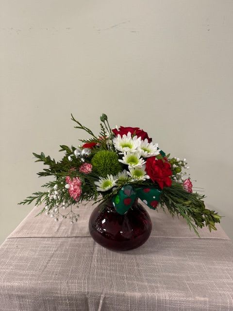 Red roses and white daisies in a round glass vase with a bow