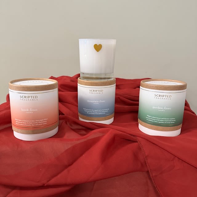 Three scented candles on red fabric, one with a gold heart icon