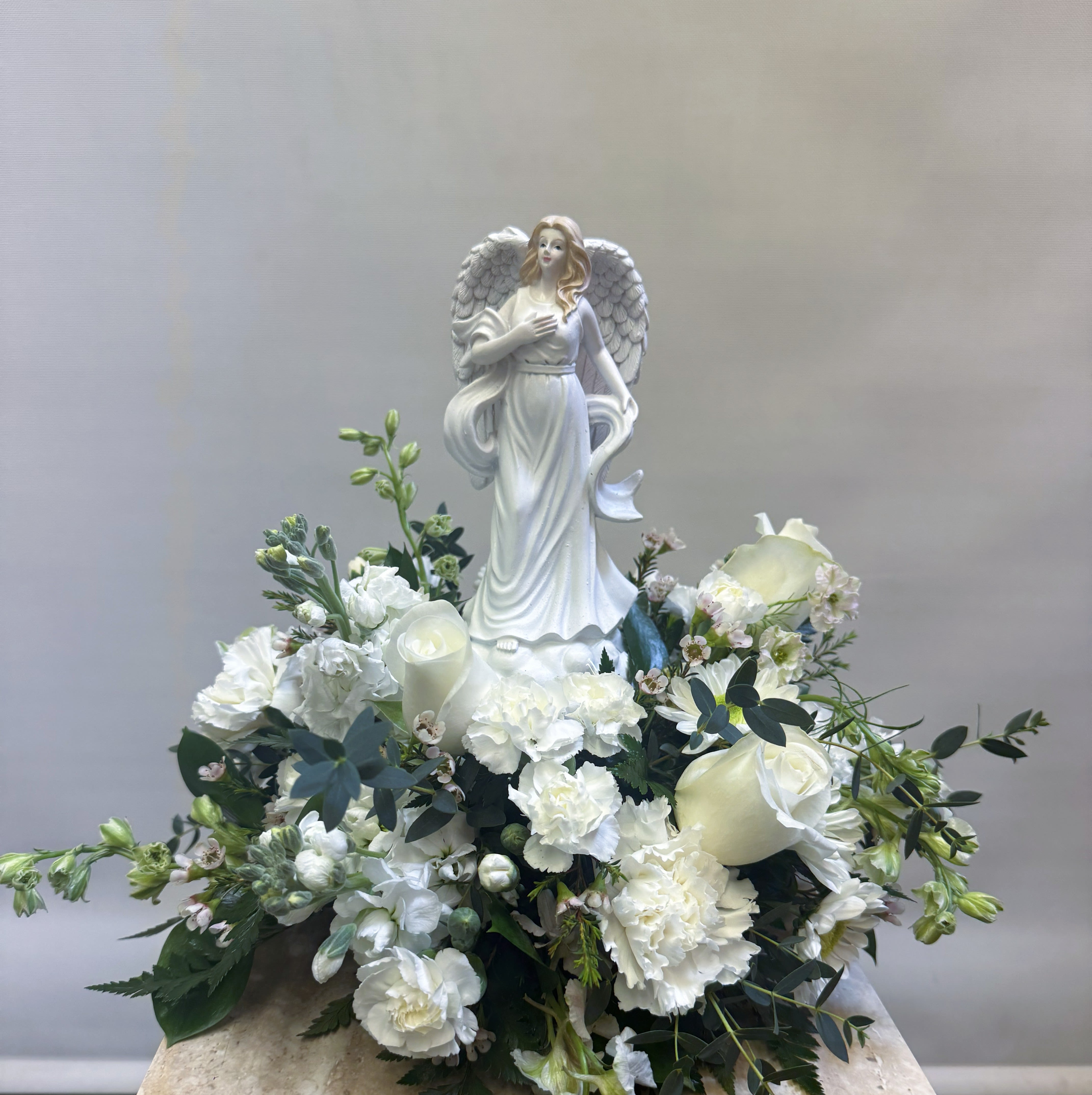 Musical Angel Arrangement  - Bouquet will be delivered approximately as pictured. Features a musical box angel that plays a hymn, with a beautiful all white, fresh arrangement surrounding the bottom. Perfect for a sympathy arrangement because it is something the family would be able 