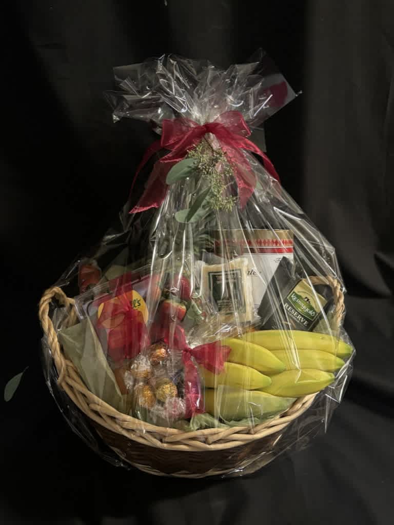 Gift basket with bananas, chocolates, and packaged snacks wrapped in clear cellophane