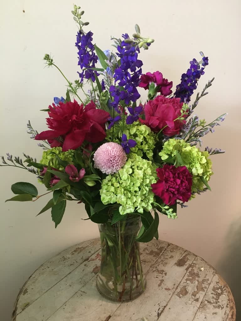 Mixed bouquet in a clear glass vase with purple, pink, and green flowers
