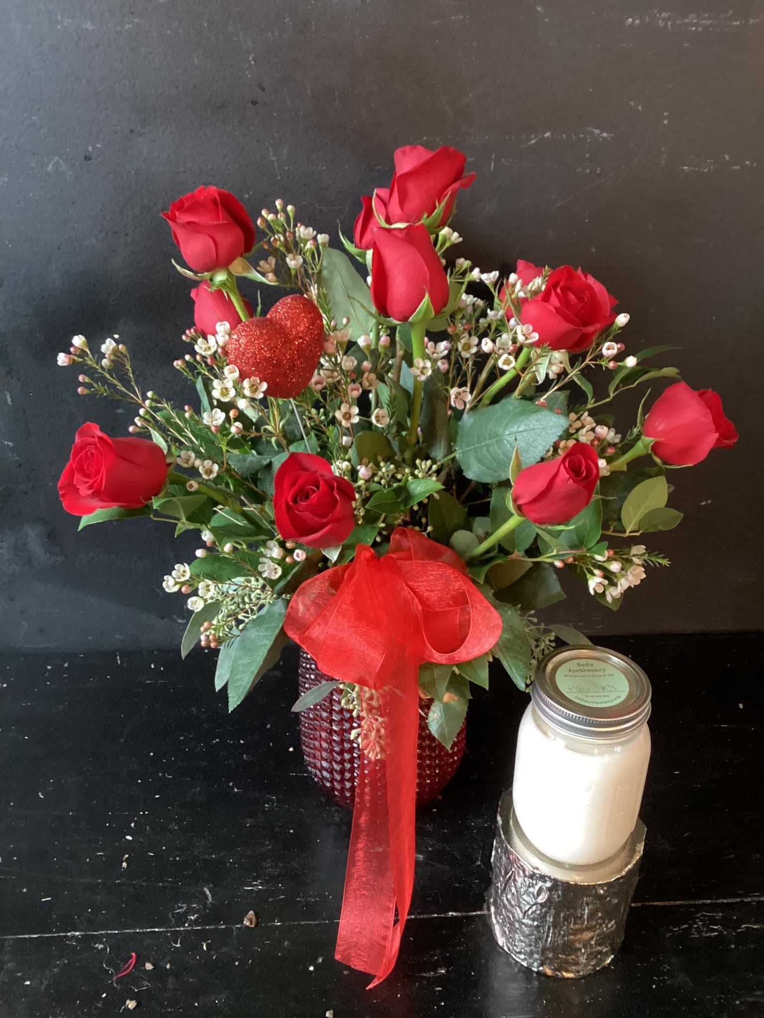Red roses in a red vase with a glittery heart pick and ribbon