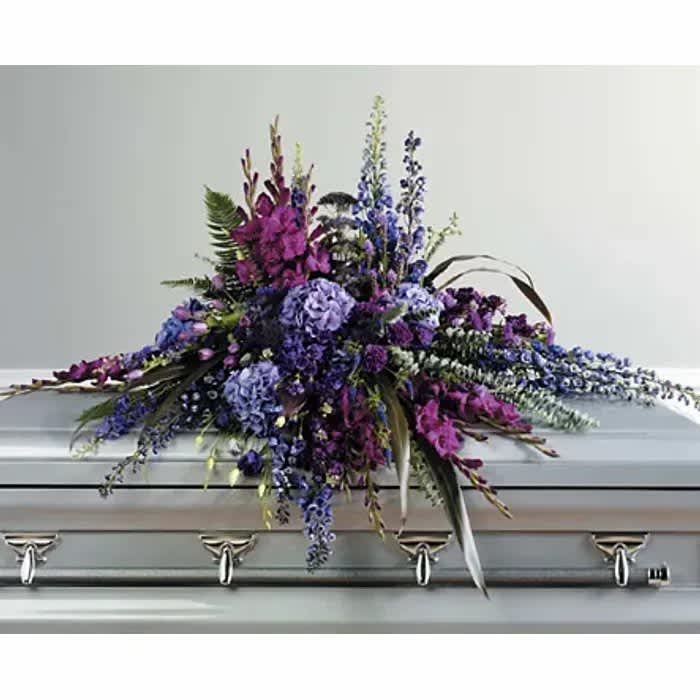 Purple and blue floral spray on a silver casket