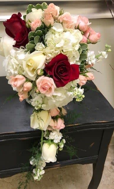 Cascade bouquet of red, white, and blush roses with white hydrangea