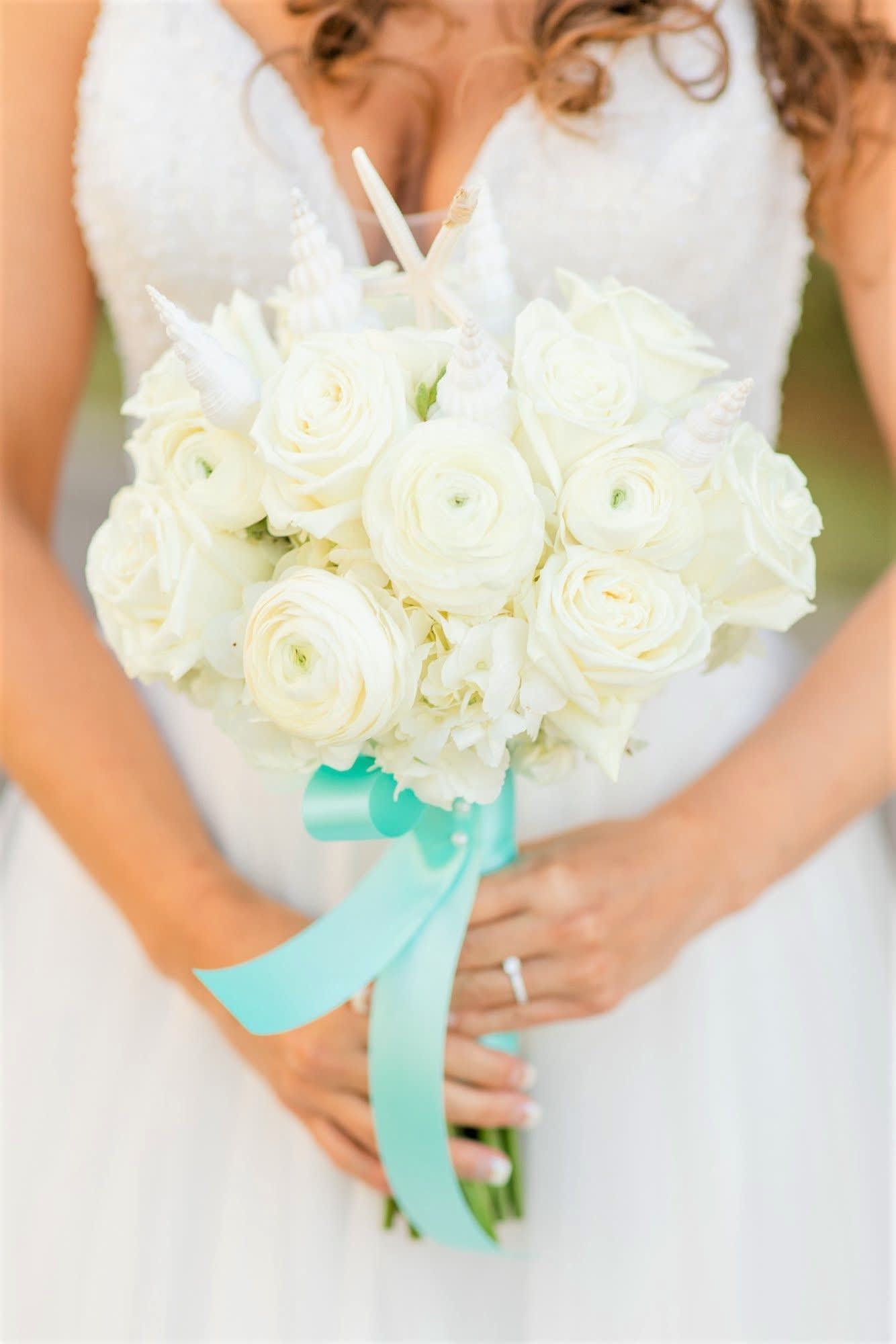 Bride holding a white rose bouquet with a turquoise ribbon