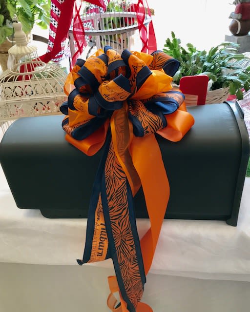 Dark green casket with a large orange and navy ribbon bow