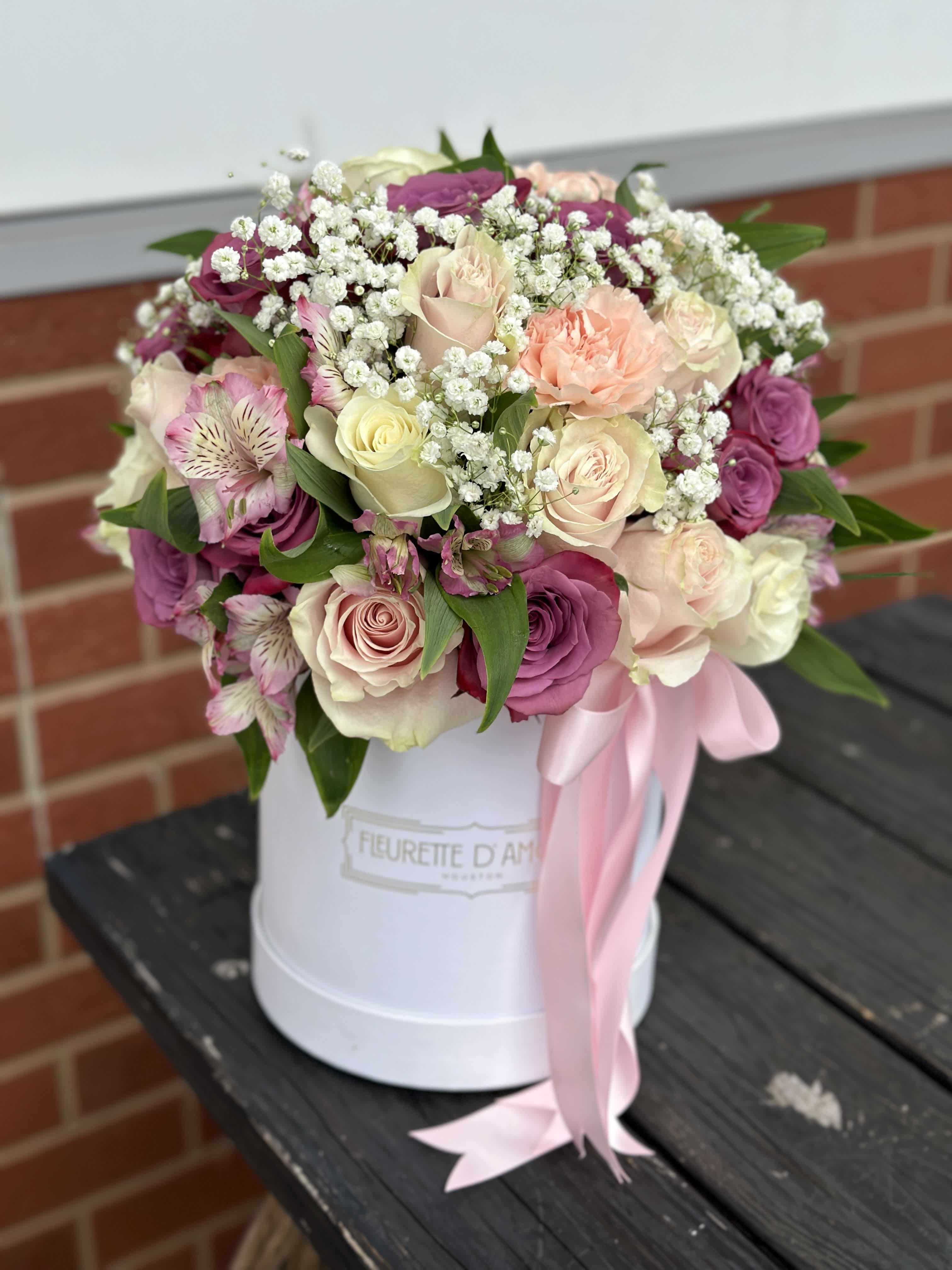 Pink and cream rose bouquet in a white hat box with a pink ribbon