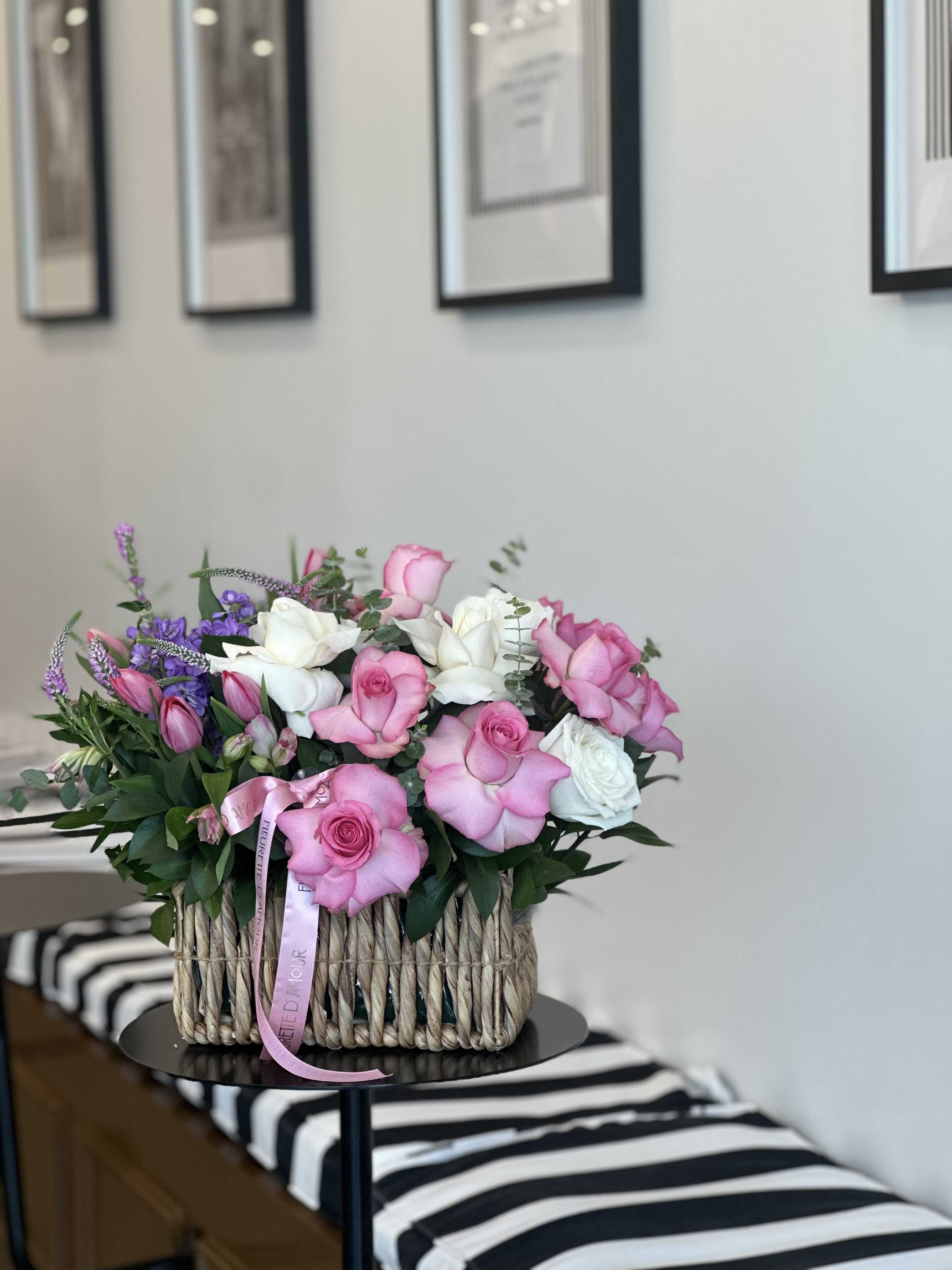 Pink and white roses arranged in a woven basket