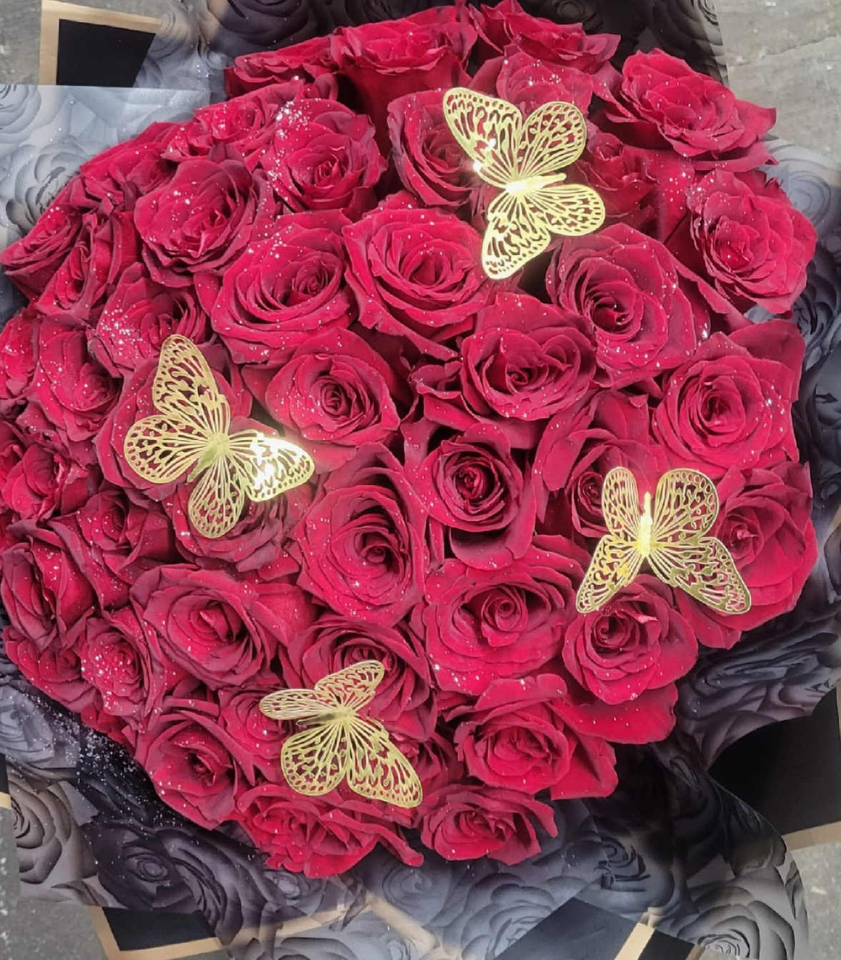 Round bouquet of deep pink roses with gold butterfly accents