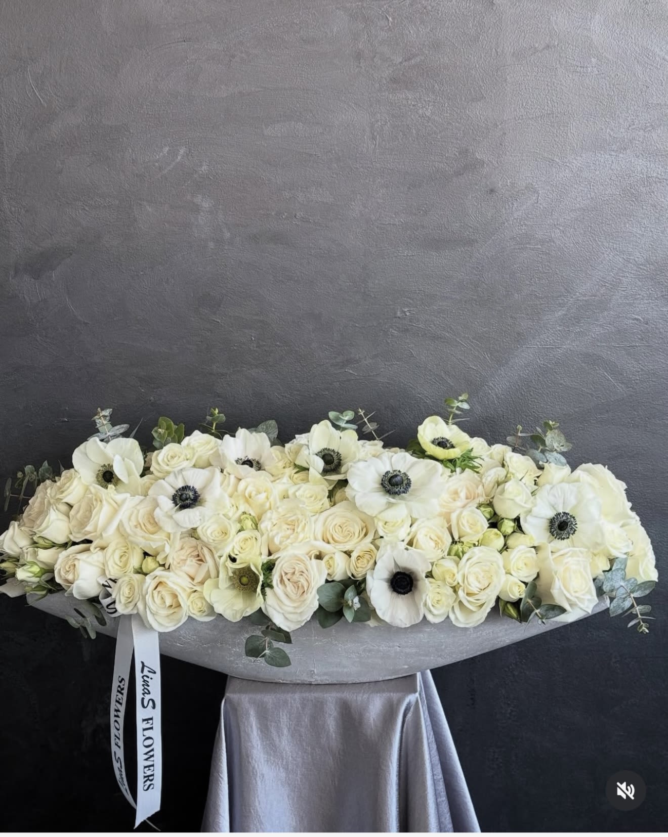 Long white floral arrangement with roses and anemones in a low container