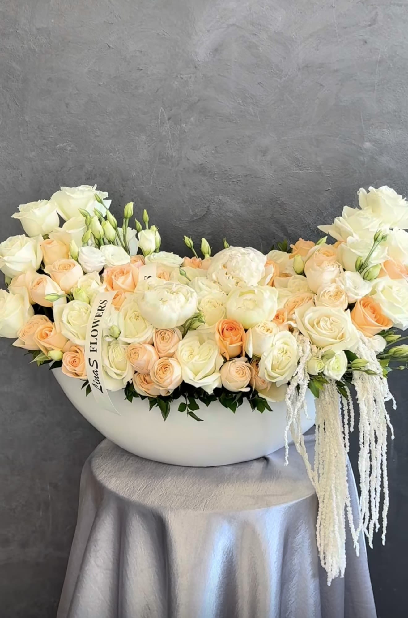 Cream and peach roses arranged in a white bowl-shaped vase