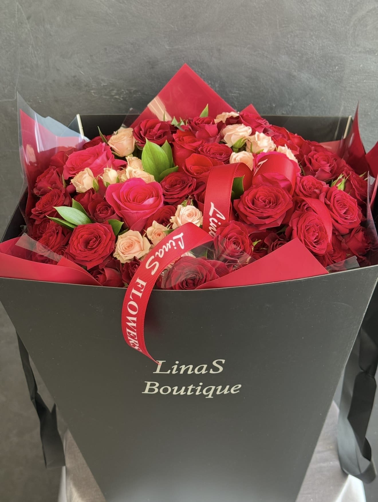 Bouquet of red and blush roses in a black gift box with a red ribbon