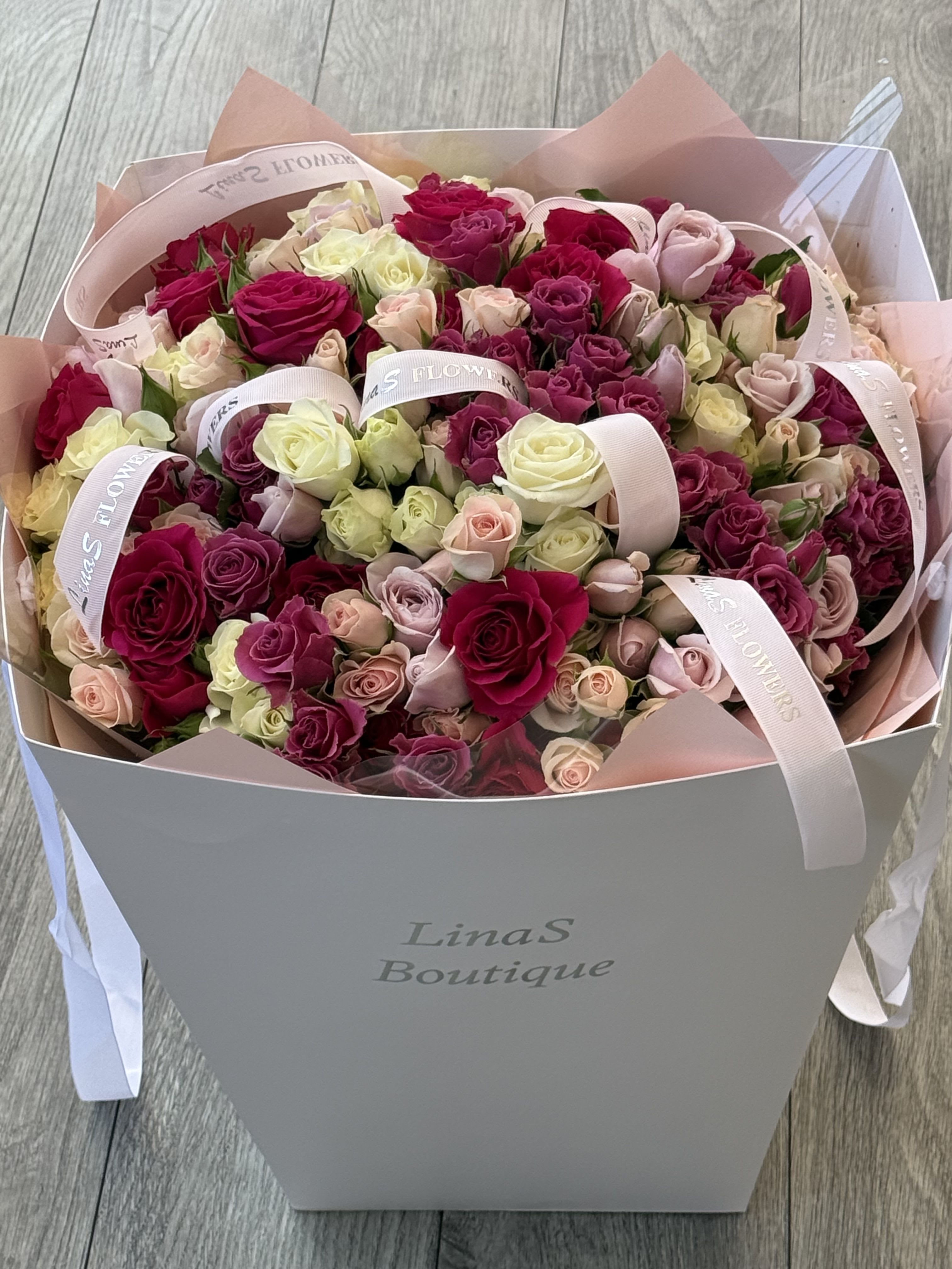 Bouquet of pink, cream, and red roses in a gift box