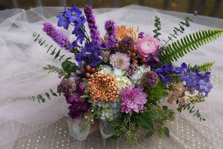 Colorful bouquet with purple, pink, and orange flowers on white tulle