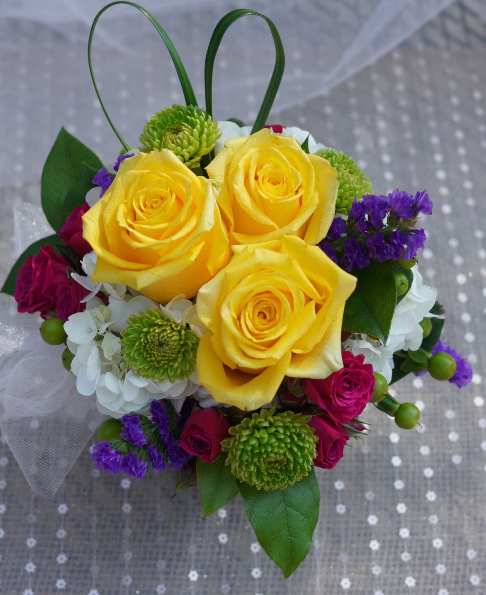 Yellow roses with purple and white flowers in a small bouquet