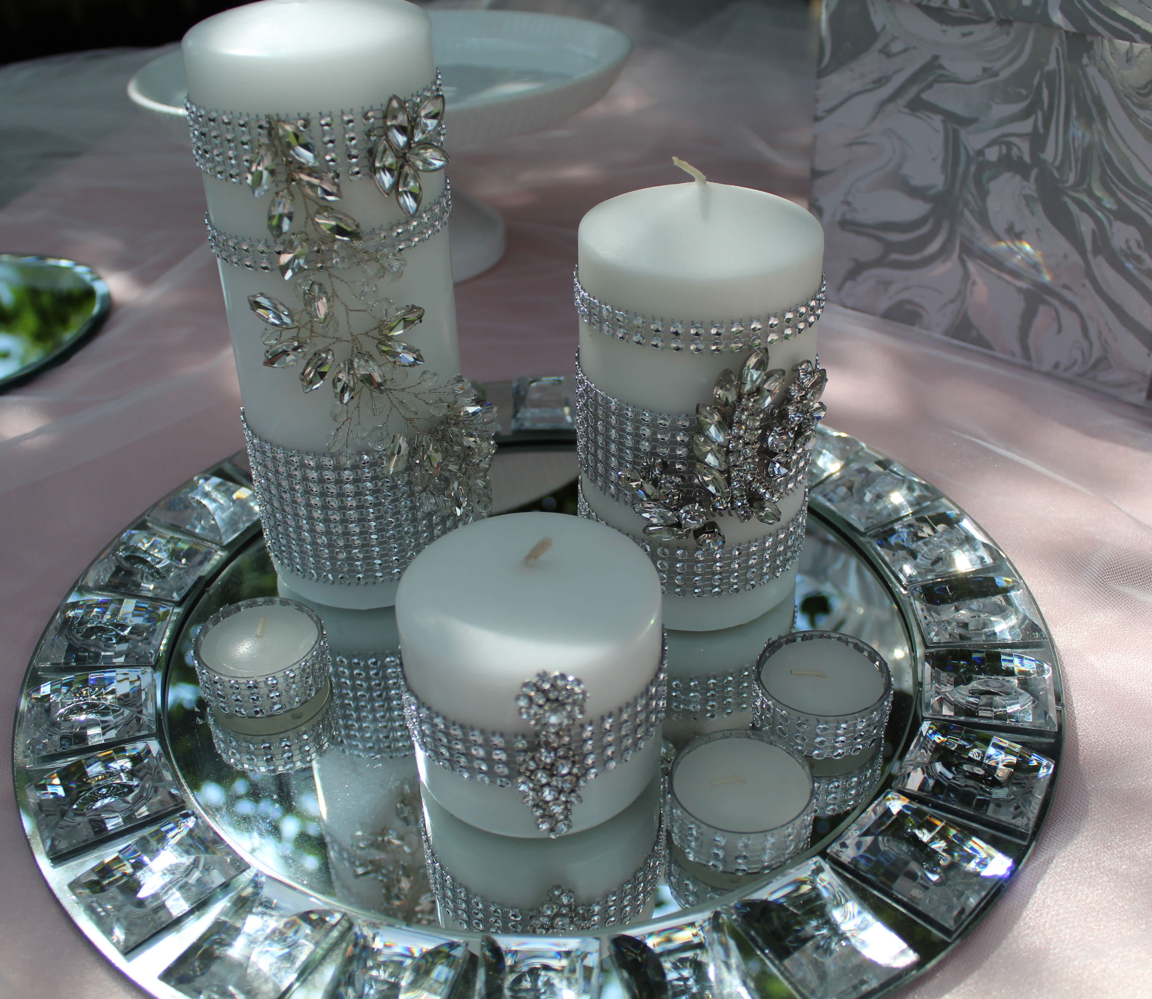 White candles decorated with rhinestones on a mirrored tray