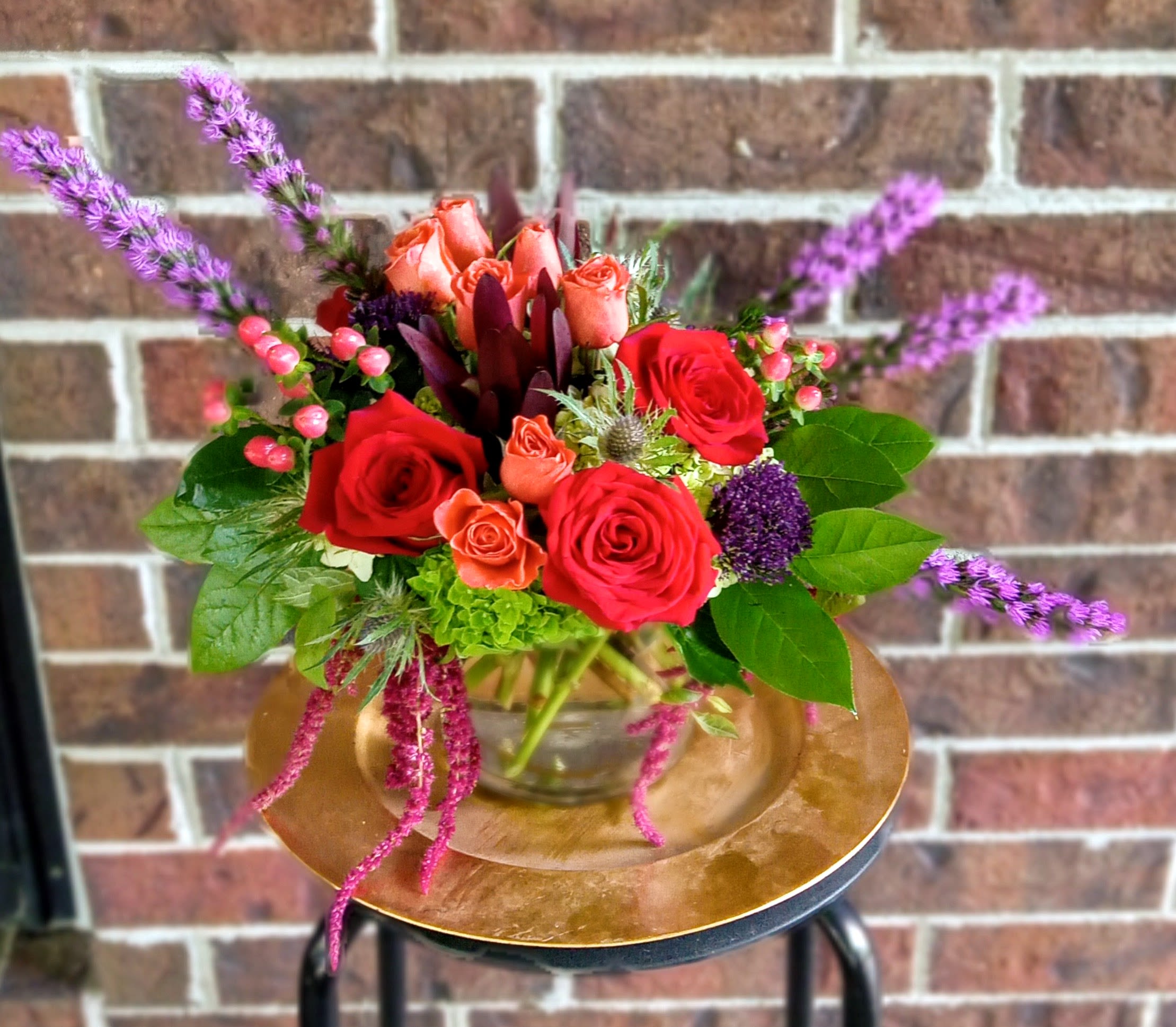 Bowl of Joy by BloomNation™ - There are a lot of things you don’t want overflowing. Your basement. Most rivers. Your basement again. This classic glass bubble bowl, on the other hand, is overflowing with beautiful flowers, red roses, purple liatris, orange spray roses, hypericum berries, hanging amaranthus and purple flora-jean carnations,  it’s a wonderful thing to behold.  If you want to put an abundance of joy in your life, or the life of a loved one, this arrangement is overflowing with joy, love &amp; happiness!