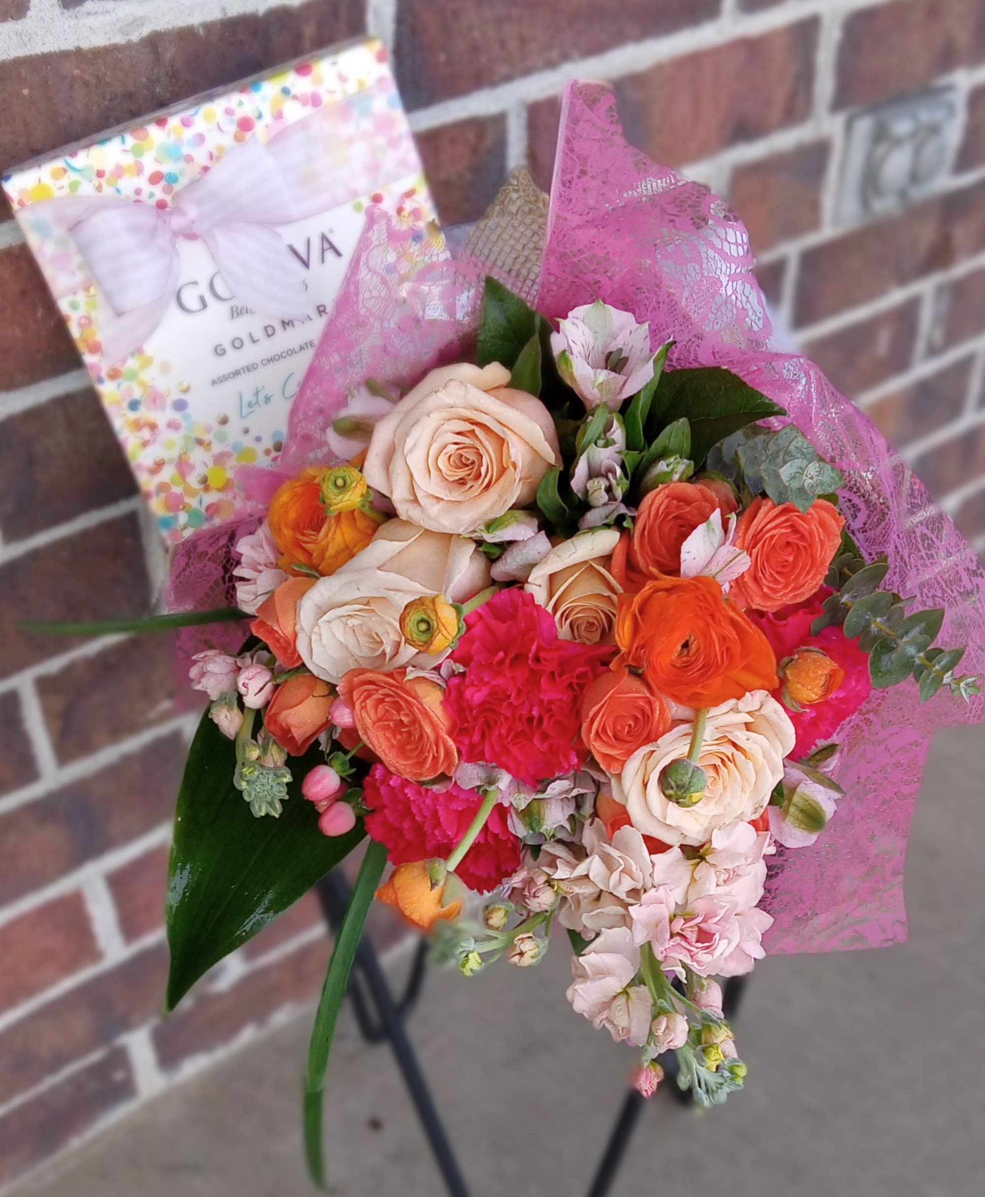Bouquet of peach and coral roses with pink flowers and a chocolate box