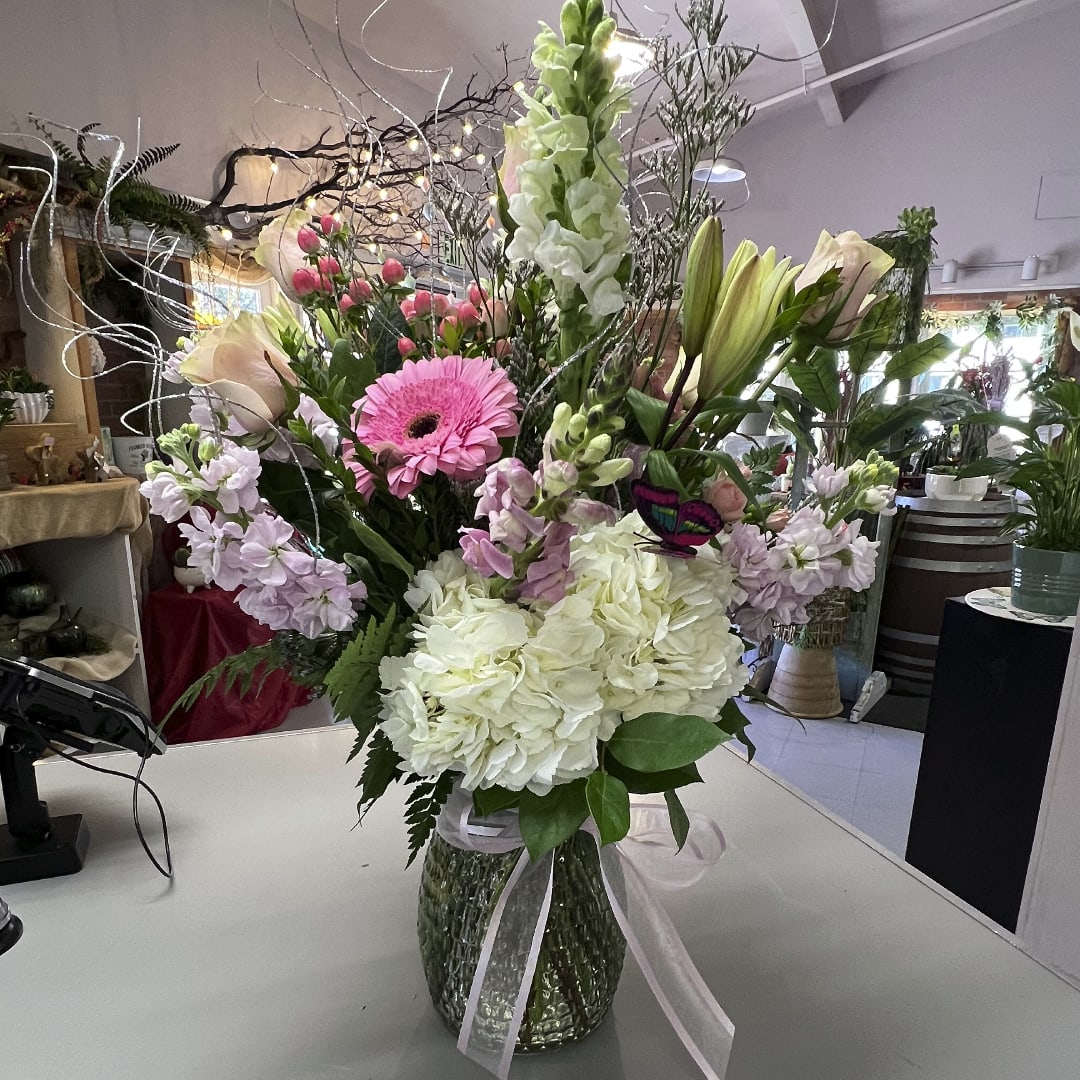 Tall mixed flower arrangement in a glass vase with pink and white blooms