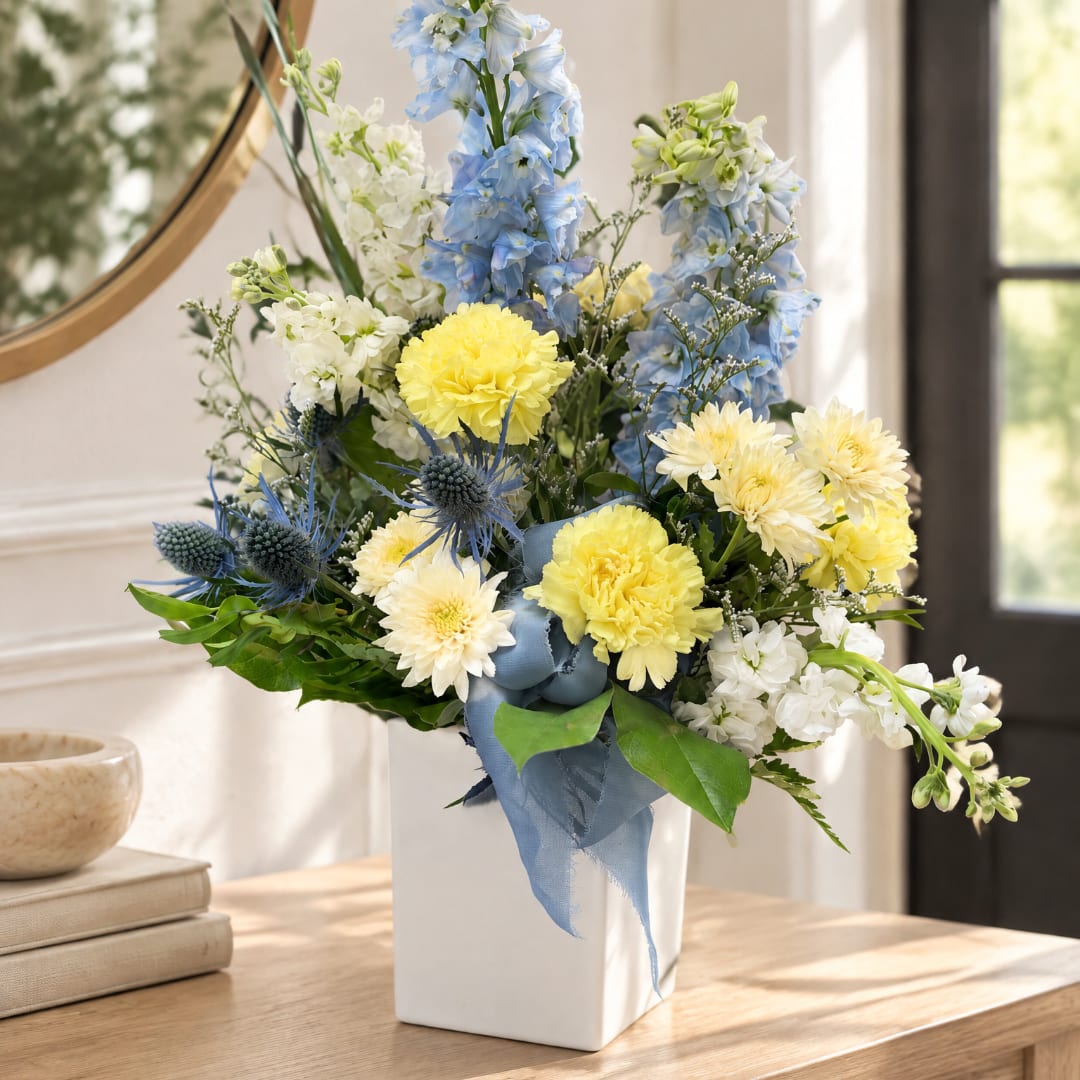 Blue and yellow floral arrangement in a white vase