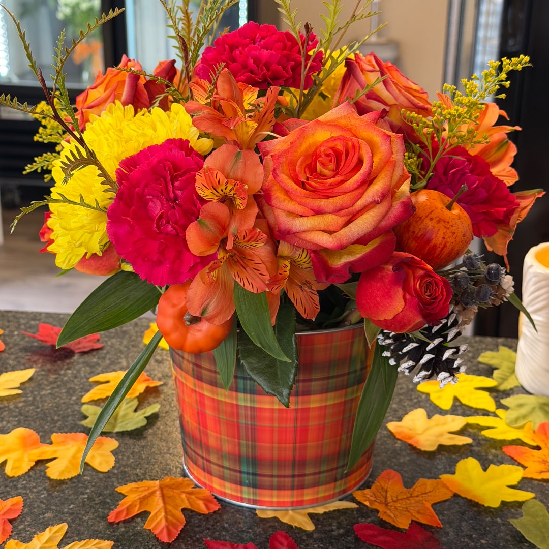 Fall bouquet in a plaid tin container with roses, mums, and orange flowers