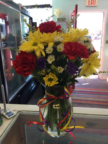 Bouquet of red and yellow flowers in a glass vase with ribbon