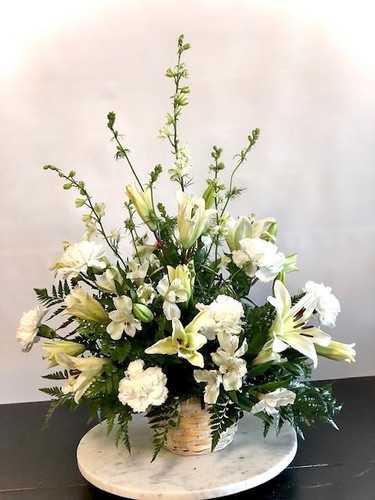 White lilies and carnations in a wicker basket arrangement